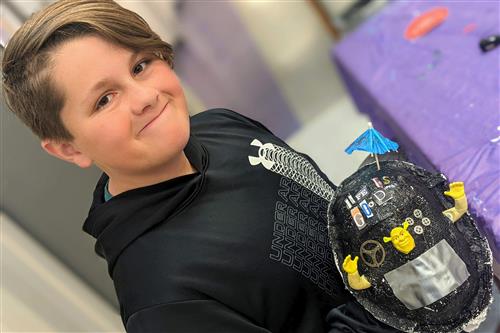 Student at Fine Arts summer camp smiling with his artwork